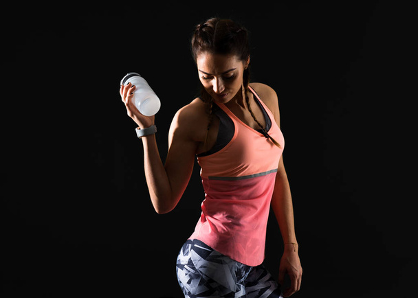 Sport nő a sötét háttér előtt egy üveg - Fotó, kép