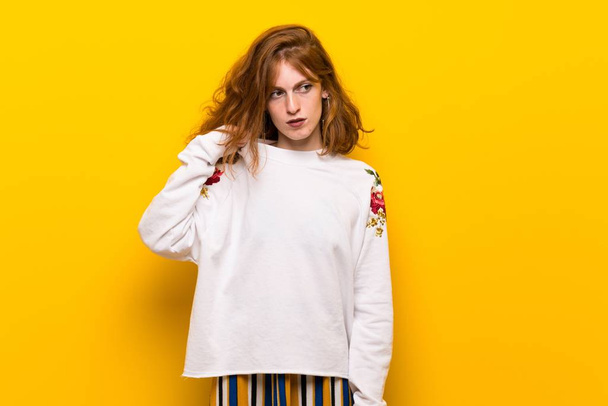 Jonge roodharige vrouw over gele muur met moe en ziek expressie - Foto, afbeelding