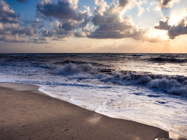 Auringonlasku ranta karkea meret ja kaatuu aallot
. - Valokuva, kuva