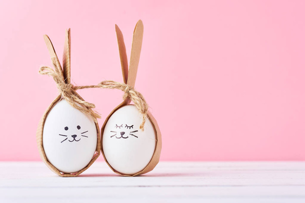 Huevos caseros divertidos con caras sobre un fondo rosa. Concepto de Pascua o pareja feliz
 - Foto, Imagen