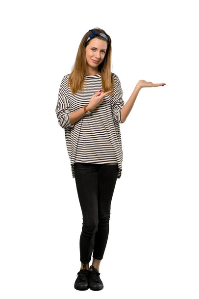 A full-length shot of a Young woman with headscarf holding copyspace imaginary on the palm to insert an ad over isolated white background - Zdjęcie, obraz