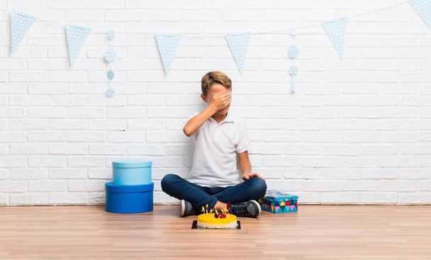 boy celebrating his birthday with a cake covering eyes by hands - 写真・画像
