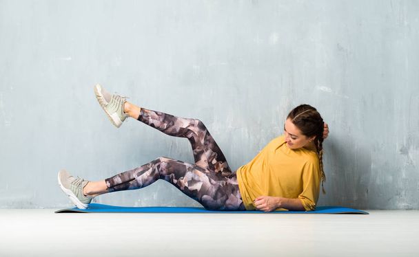Sport woman over grunge wall with mat - Photo, Image