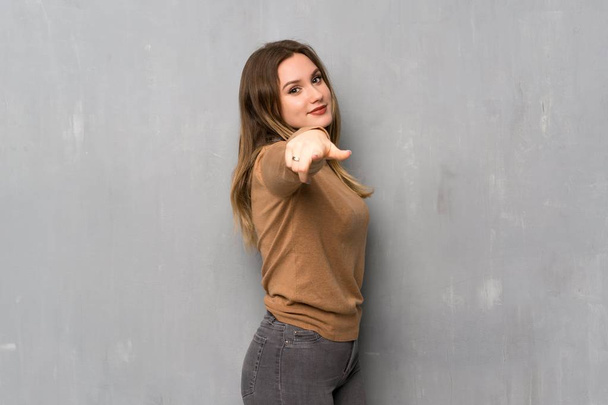 Дівчина-підліток над текстурованою стіною вказує пальцем на вас з впевненим виразом
 - Фото, зображення