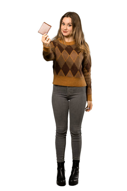 A teljes hosszúságú lövés egy tinédzser lány, barna pulóvert gazdaság egy pénztárca, mint elszigetelt fehér háttér - Fotó, kép