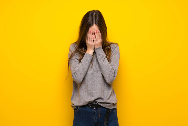 Jovem mulher sobre a parede amarela com expressão cansada e doente
 - Foto, Imagem