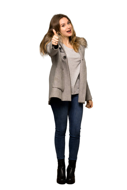 A full-length shot of a Teenager girl with coat giving a thumbs up gesture because something good has happened on isolated white background - Foto, Imagem