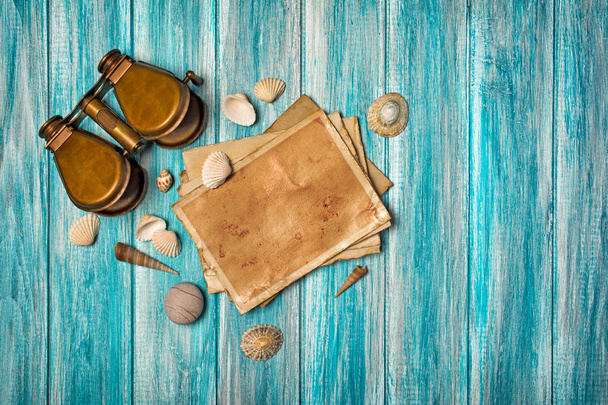 Top view on mock-up of vintage photo cards and binoculars with seashells on blue wooden background - Fotoğraf, Görsel