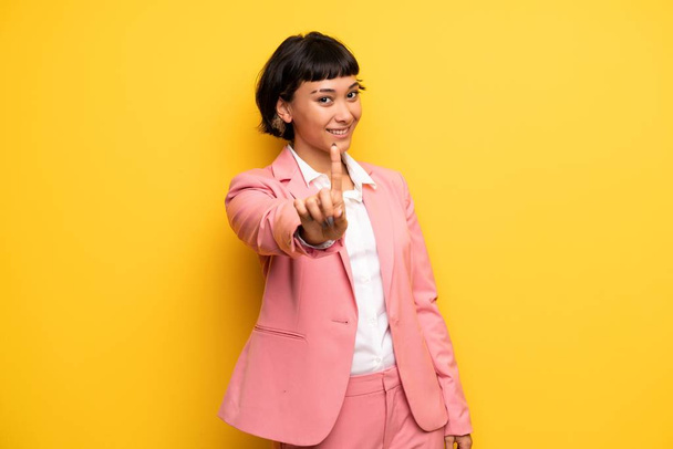 Mujer moderna con traje de negocios rosa mostrando y levantando un dedo
 - Foto, imagen