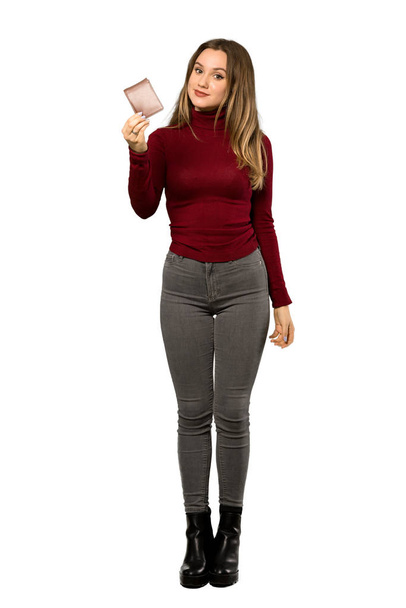 A full-length shot of a Teenager girl with turtleneck holding a wallet over isolated white background - Photo, Image