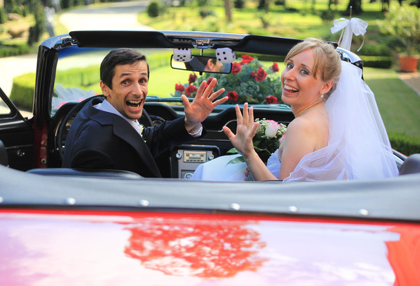 Joven pareja de boda saludando en coche cabriolet
 - Foto, imagen