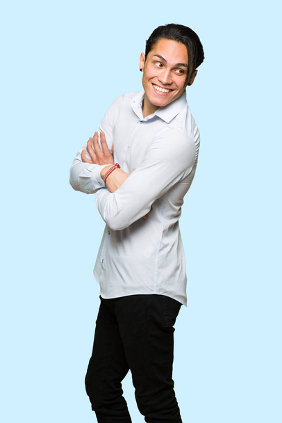 Hombre guapo mirando por encima del hombro con una sonrisa sobre un fondo azul aislado
 - Foto, Imagen