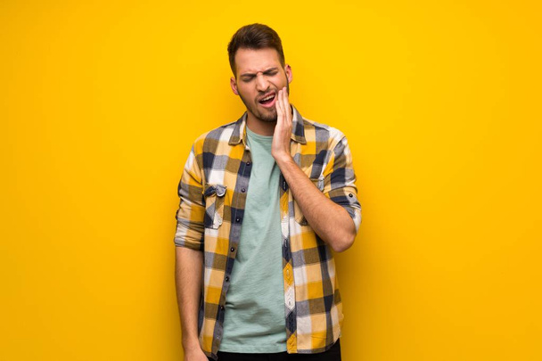 Handsome man over yellow wall with toothache - Foto, afbeelding