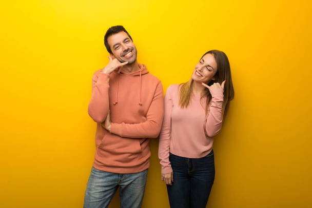 Group of two people on yellow background making phone gesture. Call me back sign - Fotografie, Obrázek