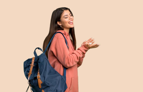 Chica adolescente con sudadera y mochila aplaudiendo después de la presentación en una conferencia sobre el fondo de color
 - Foto, imagen