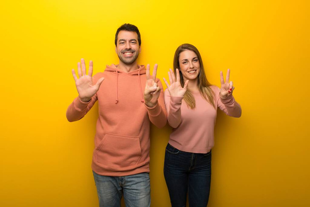 Group of two people on yellow background counting seven with fingers - Photo, Image
