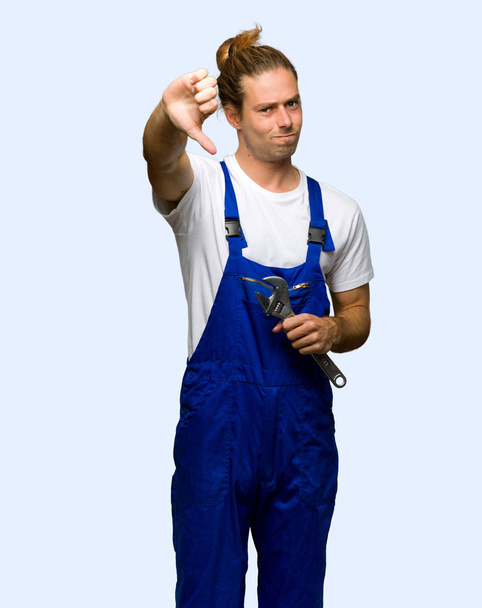 Workman showing thumb down sign with negative expression on isolated background - Foto, afbeelding