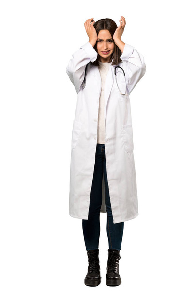 Полнометражный снимок молодой женщины-врача, расстроенной и берущейся за голову на изолированном белом фоне
 - Фото, изображение