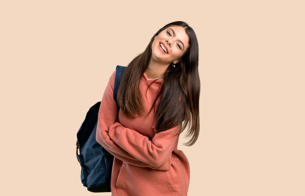 Teenager-Mädchen mit Sweatshirt und Rucksack, die Arme verschränkt, während sie auf farbigem Hintergrund lächelt - Foto, Bild