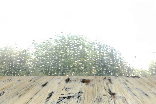 Tapa de mesa de madera lavada vacía lista para su montaje en la pantalla del producto. con gota de lluvia en el fondo de la ventana
 - Foto, imagen