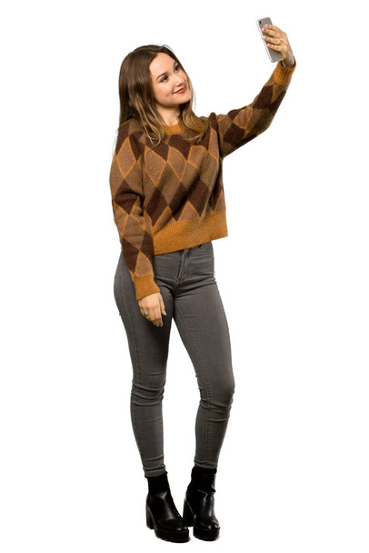 Un plan complet d'une adolescente avec un pull marron faisant un selfie sur fond blanc isolé
 - Photo, image