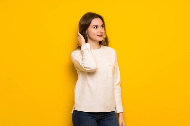 Nastolatek dziewczyna nad żółte ściany myślenie pomysł chwila drapanie głowy - Zdjęcie, obraz