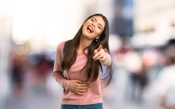 Adolescente avec chemise rose pointant du doigt quelqu'un et riant beaucoup à la ville
 - Photo, image
