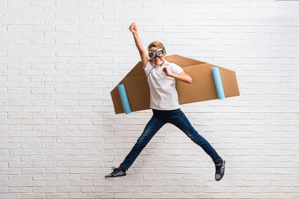 Boy playing with cardboard airplane wings jumping - Photo, Image