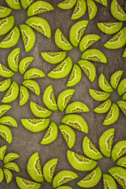 Kreative Blumen aus von unten geschnittenen Kiwis beleuchtet auf einem steinernen Hintergrund Ernährungskonzept - Foto, Bild