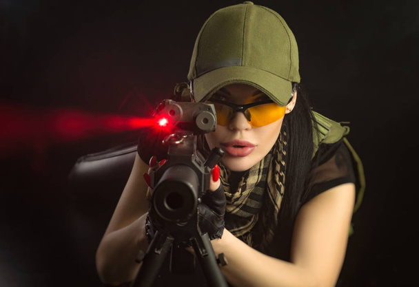 meisje in militaire speciale kleren poseren met een pistool in zijn handen op een donkere achtergrond in de nevel - Foto, afbeelding