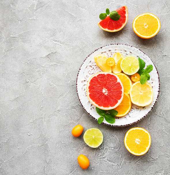 Plate with citrus fresh fruits on a concrete background - Photo, Image