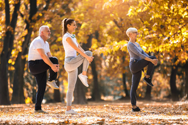 Старший мужчина и женщина и молодая женщина инструктор тренировки на свежем воздухе. Активный отдых на открытом воздухе, здоровый образ жизни, сильные тела, фигуры в форме. Стильная, современная спортивная одежда. Разные поколения
 - Фото, изображение
