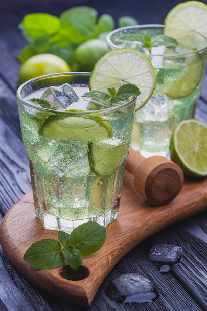 Two glasses of refreshing cold mojito with ice on a black wooden table - Foto, imagen