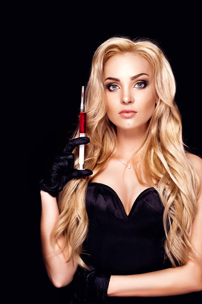 Beautiful blonde woman with curly hair holding a syringe with a remedy - Foto, immagini