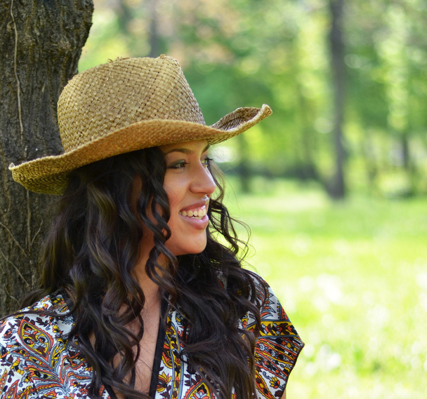 Красивая женщина в соломенной шляпе прислонилась к дереву
 - Фото, изображение