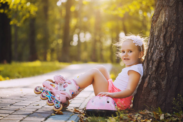 Souriant Petite fille sur patins à roulettes au parc d'été
 - Photo, image
