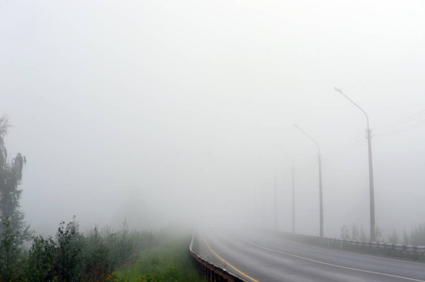 Un camino vacío desapareciendo en la densa niebla matutina
. - Foto, imagen