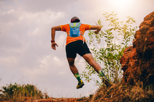 Mies juoksee polkua. ja urheilijan jalat yllään urheilukengät polku käynnissä vuorilla
 - Valokuva, kuva