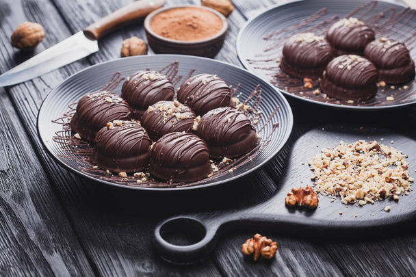 delicious fresh mini chocolate cakes with walnut on a black wooden table - Фото, зображення