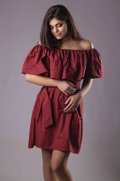 Young brunette woman in red dress posing on grey background - Foto, Imagem