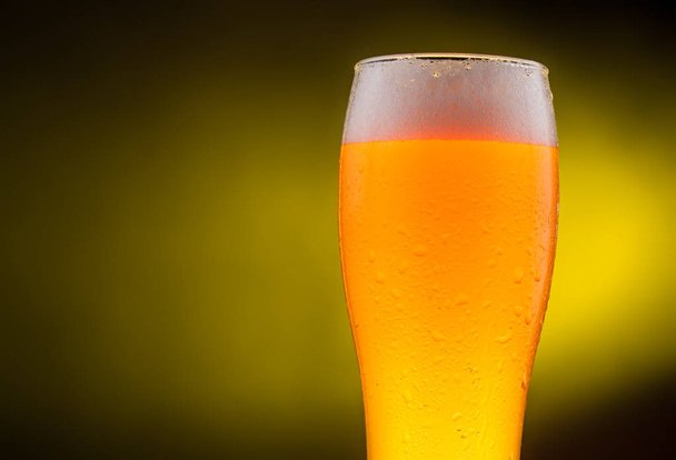 Cold light Beer in a glass with water drops. Pint of Beer close up isolated on yellow color background. - Фото, зображення