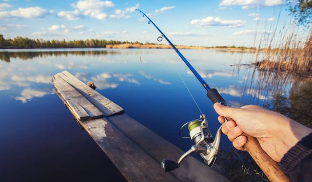 hand with spinning and reel on the summer lake - Fotoğraf, Görsel