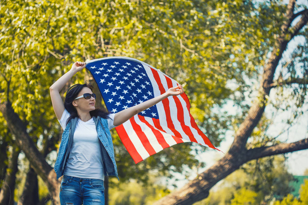 屋外でのアメリカ国旗と幸せ笑顔若い女性。7 月 4 日独立記念日 - 写真・画像