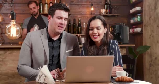 Ένας άνδρας και μια γυναίκα σε ένα μεσημεριανό διάλειμμα κοιτάζοντας το laptop και το γέλιο - Πλάνα, βίντεο