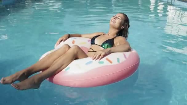 Sexy vrolijke vrouw zweeft met een opblaasbare donut cirkel in het zwembad - Video
