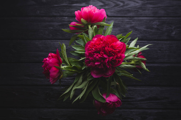 bouquet of red peonies on a black wooden background - Foto, imagen