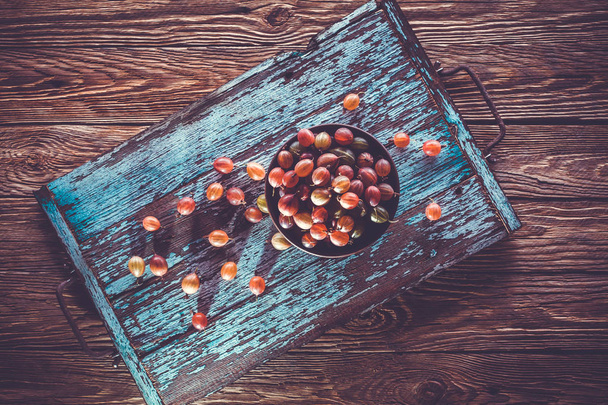 old turquoise wooden tray with gooseberry on the table. wooden background - Foto, Bild