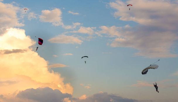 Parašutista padající z oblohy za večerního západu slunce, dramatické nebe. Rekreační sport, Paratrooper silueta na barevné obloze. - Fotografie, Obrázek