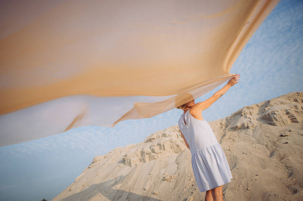 girl with a light veil and wind in the desert spread her wings - Foto, Imagen