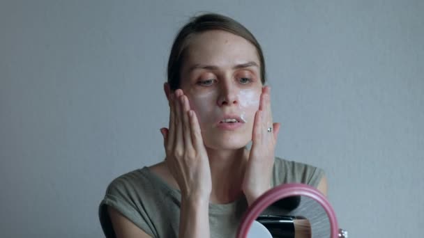 Woman puts a cream foundation on the face. Female at home ordinary day of life - Filmagem, Vídeo